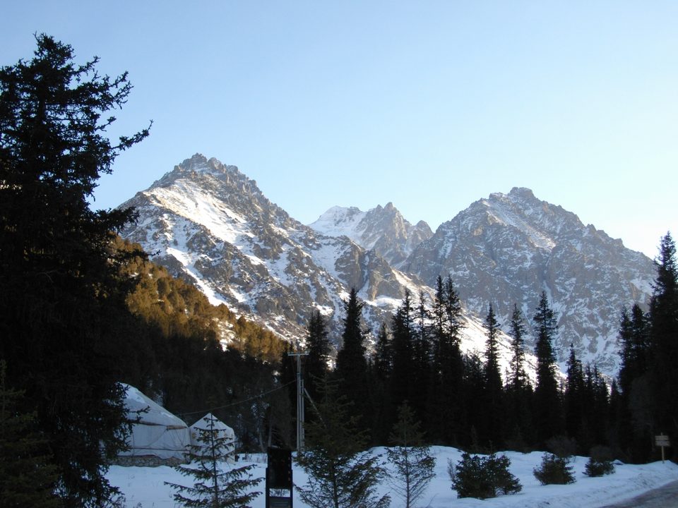 Ala-Archa mountain valley with a river, forested slopes and snowy peaks.