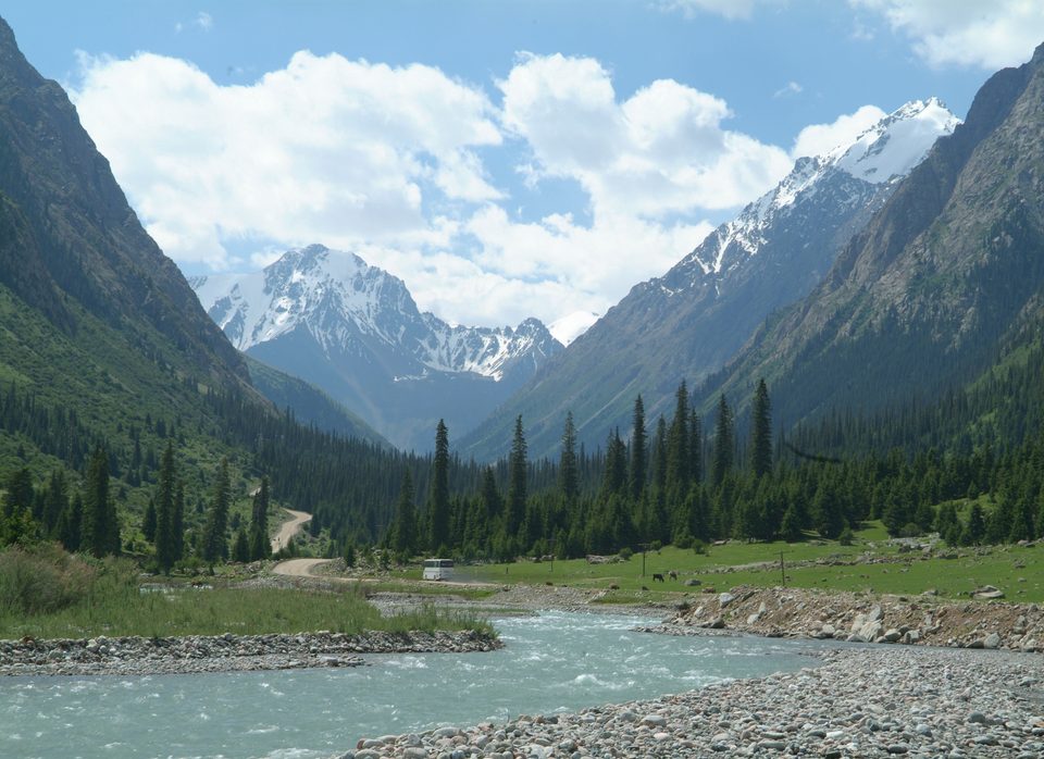 A broad view along Barskoon Gorge, with the river below snow-capped peaks.
