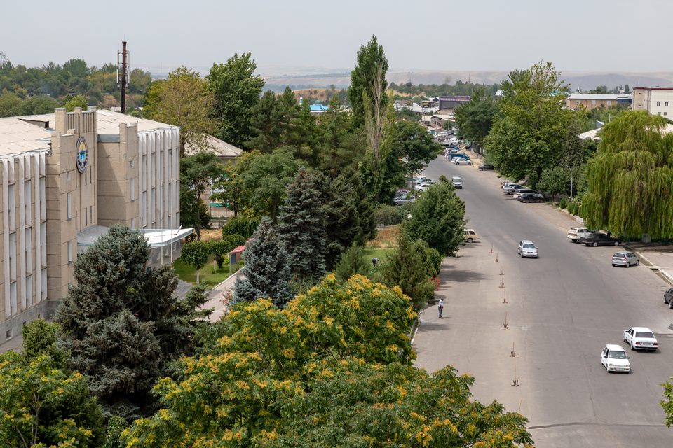 Road view between Osh and Uzgen with dry hills on the horizon.